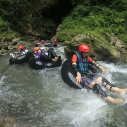 Thrill-seekers enjoy a tubing adventure through a scenic river in Semanu, Indonesia.